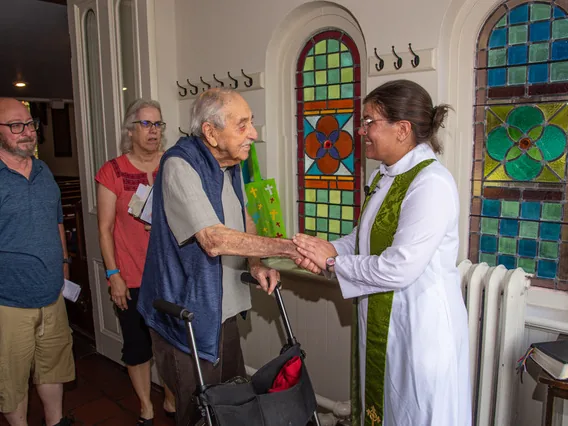 The rector greeting a parishioner with a handshake after the service